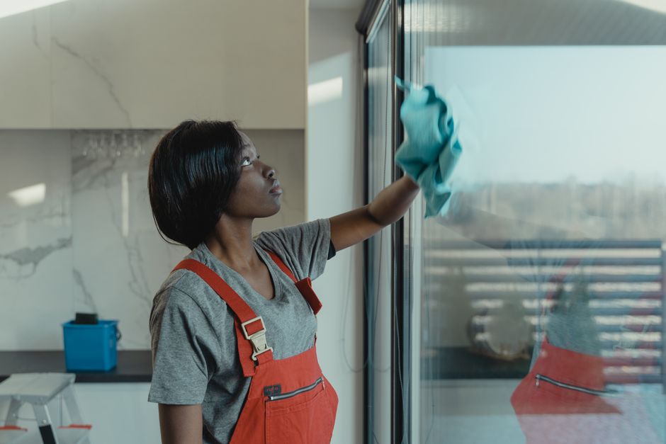 Woman using yellow rubber gloves to clean a kitchen counter with a sponge.