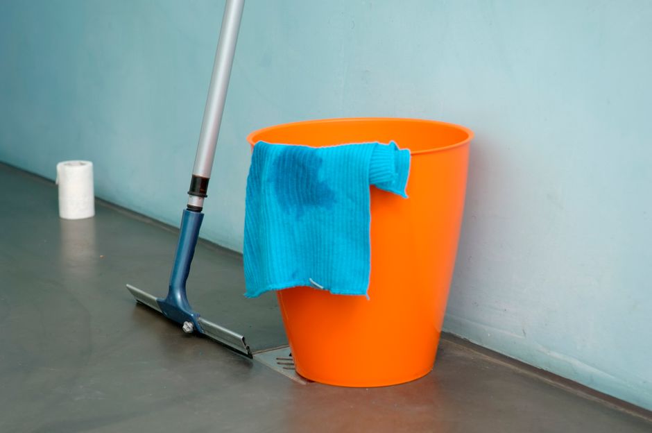 Crop anonymous person in yellow rubber protective glove wiping surface of white stylish sink with sponge and cleaning agent in modern bathroom interior